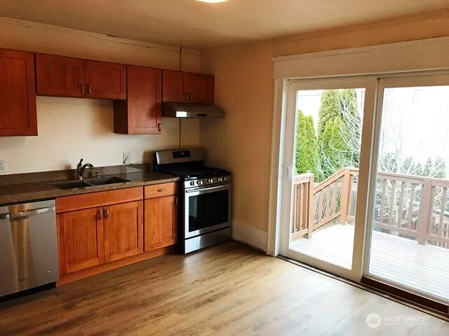 a kitchen with stainless steel appliances granite countertop a stove a sink and a refrigerator with wooden floors