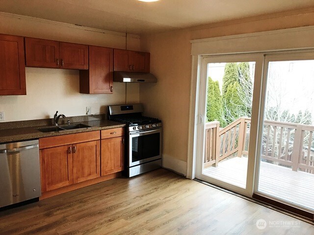 1920 East Jefferson Street, Unit B Seattle, WA 98122 - Photo 2 of 9 a kitchen with stainless steel appliances granite countertop a stove a sink and a refrigerator with wooden floors
