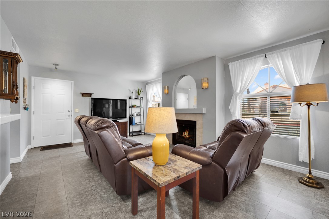 7570 West Flamingo Road, Unit 115 Las Vegas, NV 89147 - Photo 4 of 34 A well-lit living area offers comfortable seating and a cozy fireplace for relaxation.