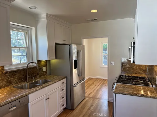 a kitchen with granite countertop a sink stove and refrigerator