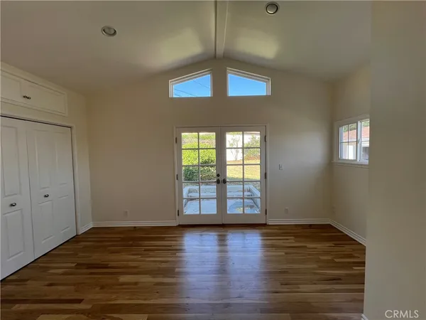 a view of an empty room with window and wooden floor