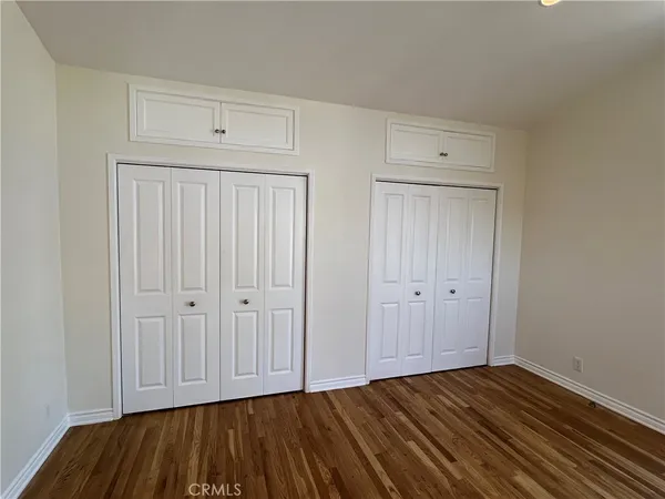 a view of an empty room with closet and wooden floor