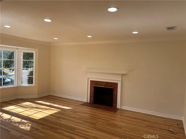 an empty room with wooden floor and fireplace