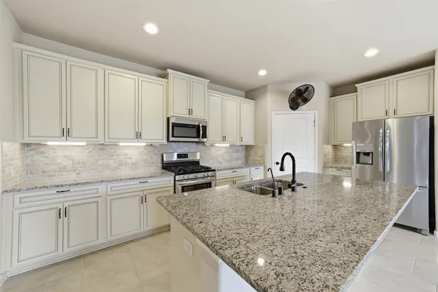 a kitchen with kitchen island granite countertop a sink stainless steel appliances and white cabinets