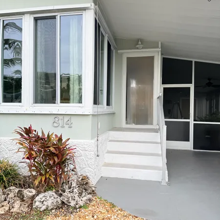 a kitchen with stainless steel appliances granite countertop a stove top oven a sink a refrigerator and white cabinets with wooden floor