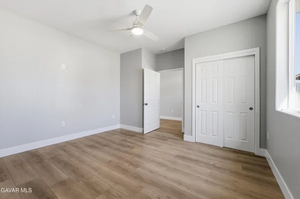 an empty room with wooden floor and ceiling fan