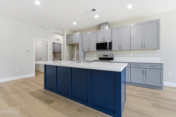 a kitchen with kitchen island granite countertop a sink cabinets and stainless steel appliances