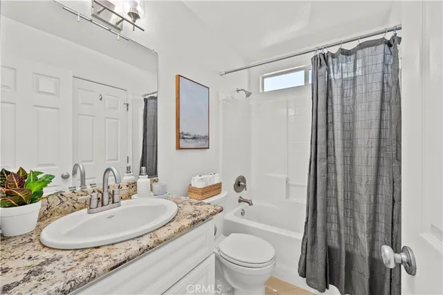 a bathroom with a granite countertop sink a toilet a mirror and shower