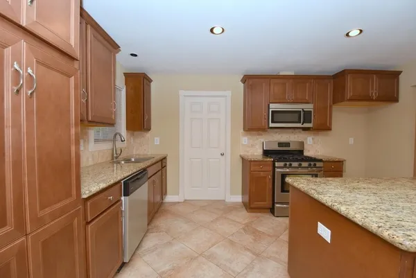 a kitchen with stainless steel appliances granite countertop a stove top oven a sink dishwasher a refrigerator and a microwave