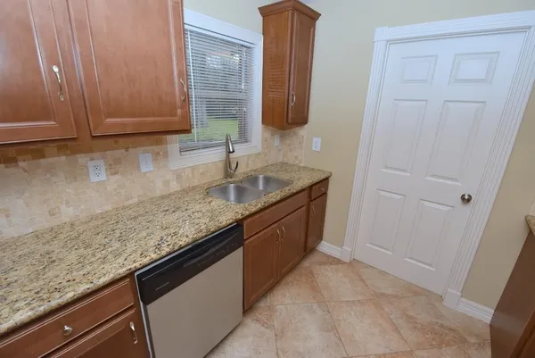 a kitchen with granite countertop a sink and a white cabinets