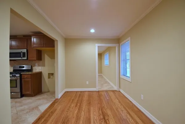 a view of empty room with kitchen and wooden floor