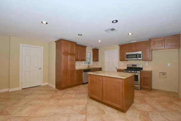 a kitchen with stainless steel appliances granite countertop a refrigerator oven a sink dishwasher and white cabinets with wooden floor