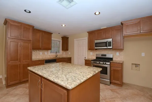 a kitchen with stainless steel appliances granite countertop a sink stove microwave and refrigerator