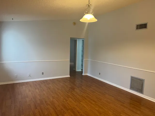 an empty room with wooden floor and chandelier