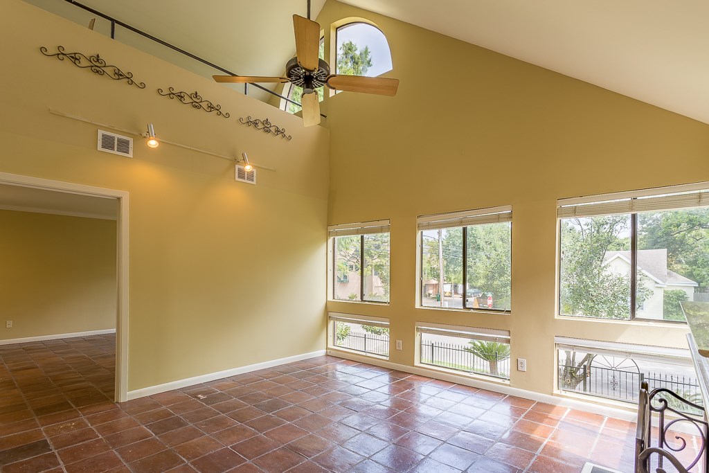 2349 Albans Road, Unit 2 Houston, TX 77005 - Photo 7 of 25 Experience the inviting warmth of this living room, featuring expansive windows that flood the space with natural light, an elegant high ceiling with a stylish fan, and a seamless flow into an adjoining room perfect for versatile living.