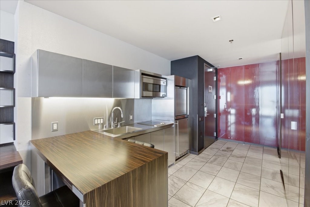 4381 West Flamingo Road, Unit 10306 Las Vegas, NV 89103 - Photo 4 of 26 This contemporary kitchen features sleek stainless steel appliances and durable tile flooring.