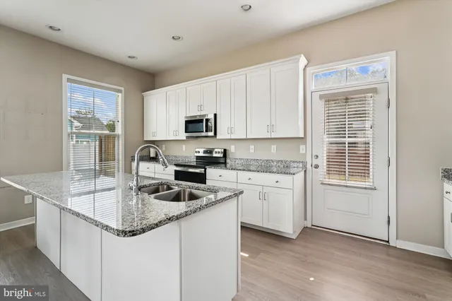 a kitchen with granite countertop a sink stove and cabinets