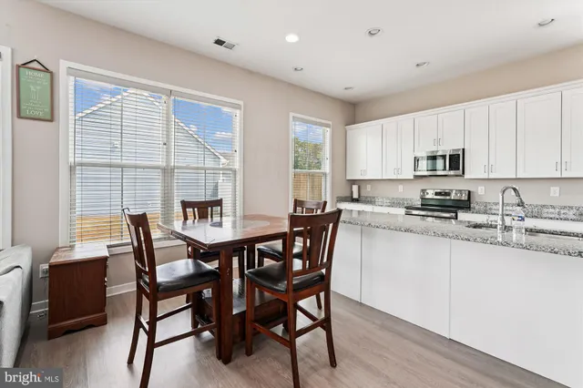 a kitchen with granite countertop a dining table chairs and a refrigerator