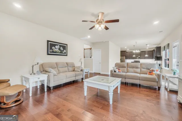 a kitchen with stainless steel appliances granite countertop a stove a refrigerator a sink dishwasher a dining table and chairs with wooden floor