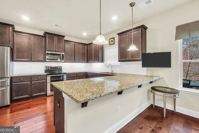 a kitchen with stainless steel appliances kitchen island granite countertop a refrigerator a sink dishwasher a oven with white cabinets and wooden floor