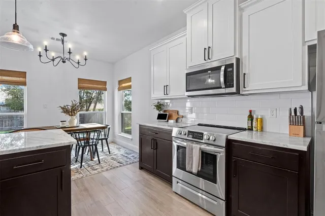 a kitchen with stainless steel appliances granite countertop a stove top oven a sink dishwasher a dining table and chairs with wooden floor