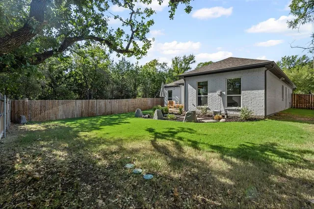 a backyard of a house with lawn chairs plants and tree