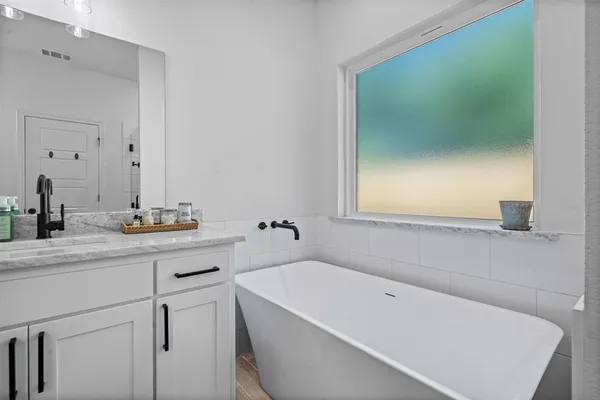 a bathroom with a tub sink and mirror