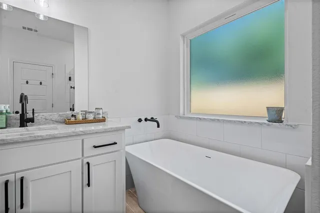 a bathroom with a tub sink and mirror
