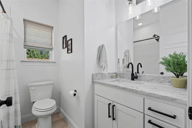 a bathroom with a granite countertop toilet sink and mirror
