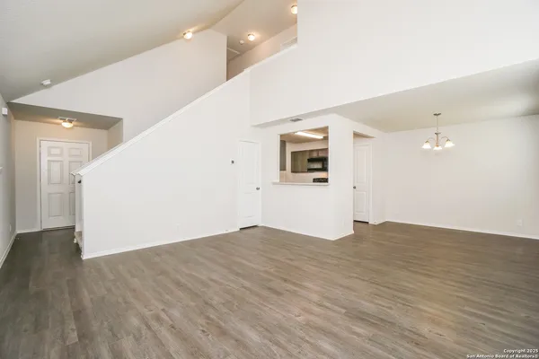 a view of a big room with wooden floor and white kitchen