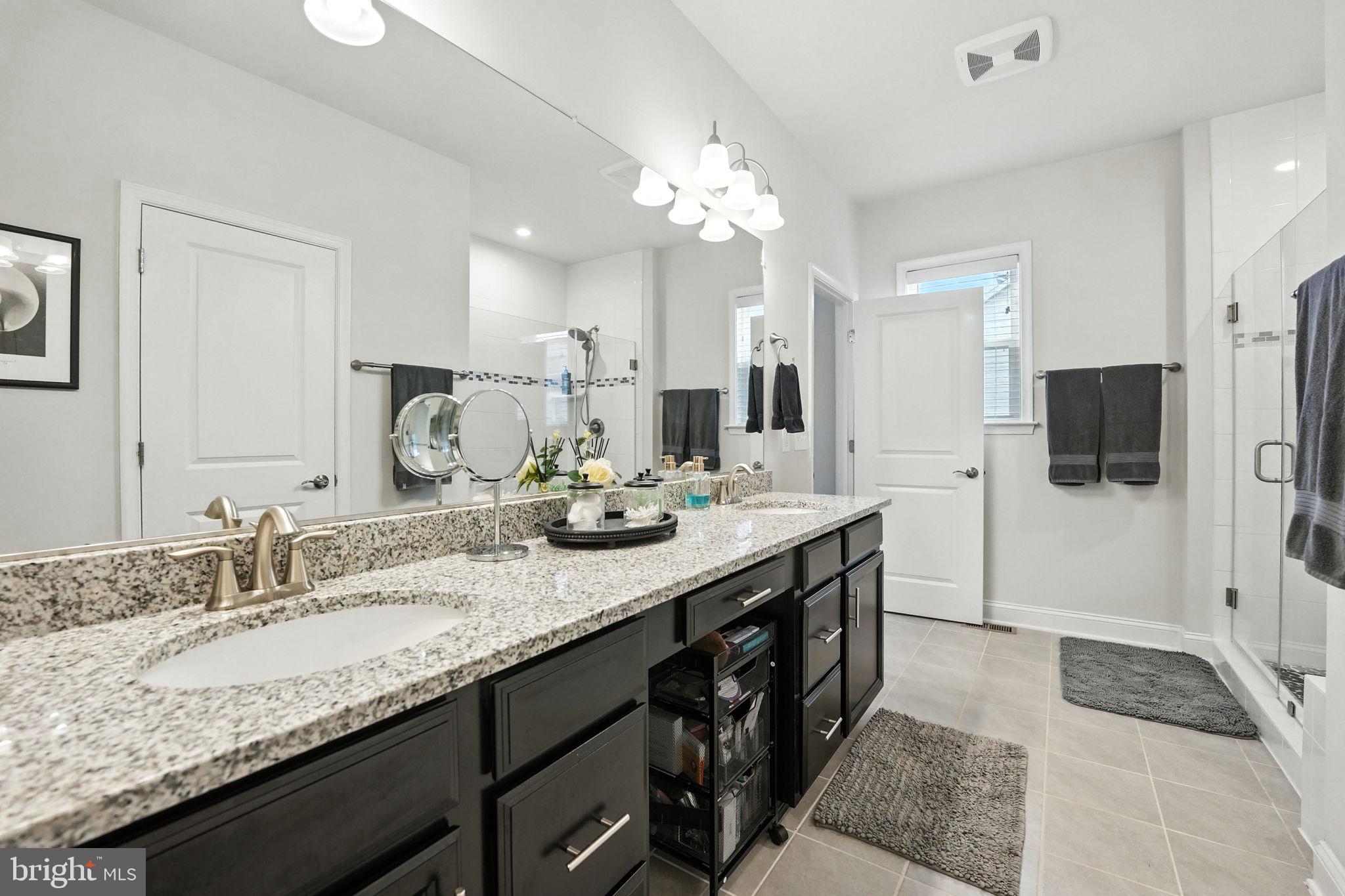 17233 Branched Oak Road Dumfries, VA 22026 - Photo 34 of 79 a spacious bathroom with a granite countertop double vanity sink a mirror and shower