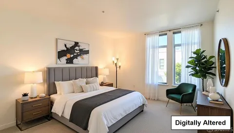 a bedroom with a bed a couch and potted plant on the dresser