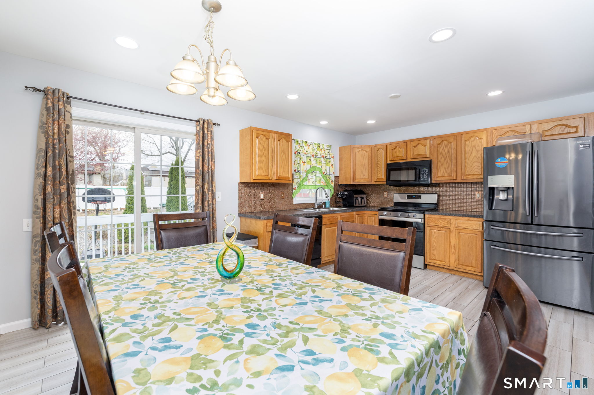 234 Traverse Street Waterbury, CT 06704 - Photo 11 of 38 a kitchen with a refrigerator a stove top oven a sink dishwasher a dining table and chairs with wooden floor