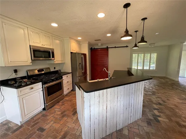 a kitchen with stainless steel appliances a stove a microwave and a refrigerator