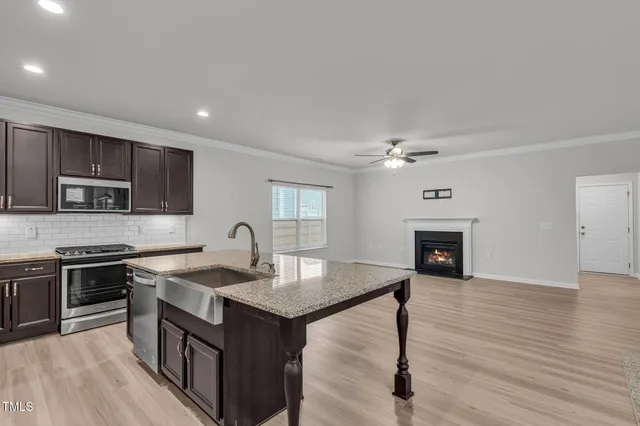 a kitchen with kitchen island granite countertop a stove top oven a sink dishwasher a dining table and chairs with wooden floor