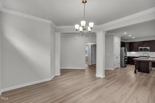 a view of a kitchen with stainless steel appliances granite countertop wooden floor and a chandelier