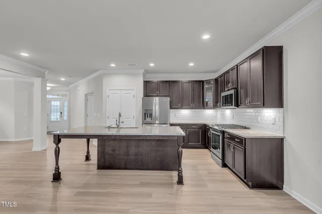 a large kitchen with stainless steel appliances a sink and cabinets
