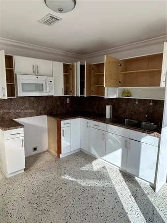 a view of a kitchen with a sink a microwave and cabinets