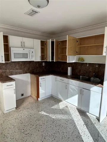 a view of a kitchen with a sink a microwave and cabinets
