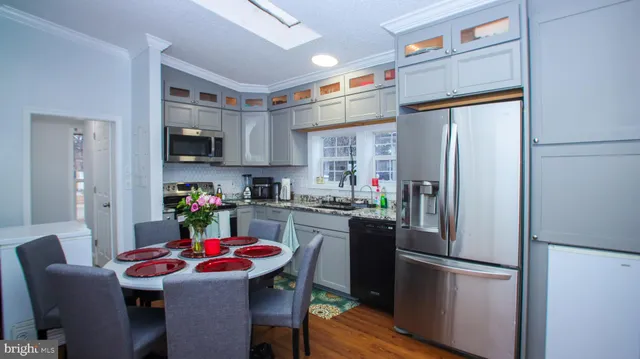 a kitchen with stainless steel appliances granite countertop a refrigerator a sink dishwasher and a refrigerator with wooden floor