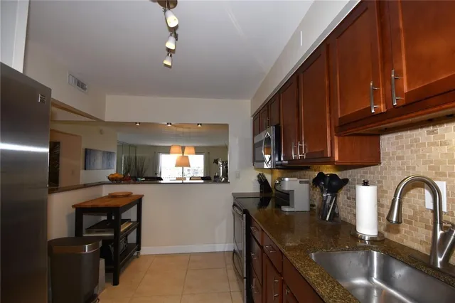 a kitchen with stainless steel appliances granite countertop a refrigerator and a stove top oven