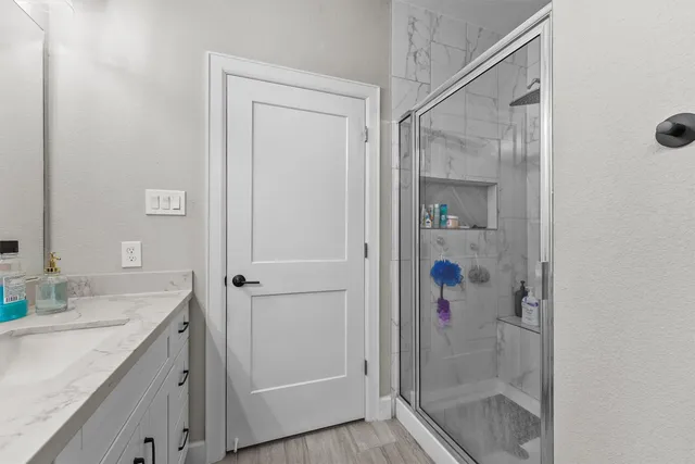 a bathroom with a granite countertop shower a sink and a mirror