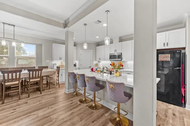 a room with stainless steel appliances a dining table wooden floor and a view of kitchen