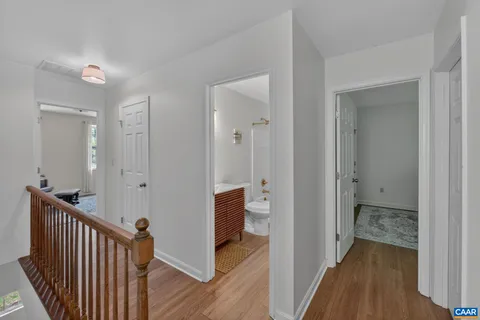 a view of a hallway with bathroom and wooden floor