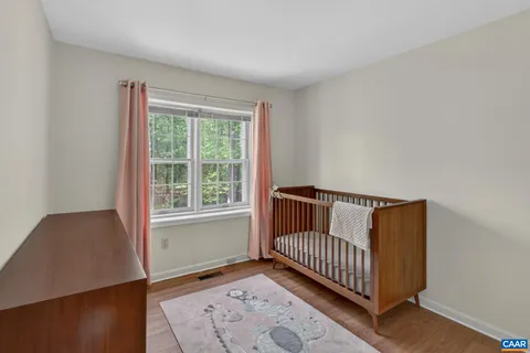 a view of a bedroom with wooden floor & a window
