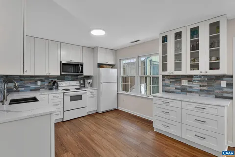 a kitchen with granite countertop white cabinets and white appliances
