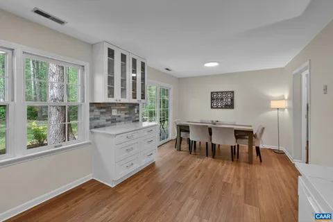a kitchen with stainless steel appliances granite countertop a stove top oven a sink dishwasher a dining table and chairs with wooden floor
