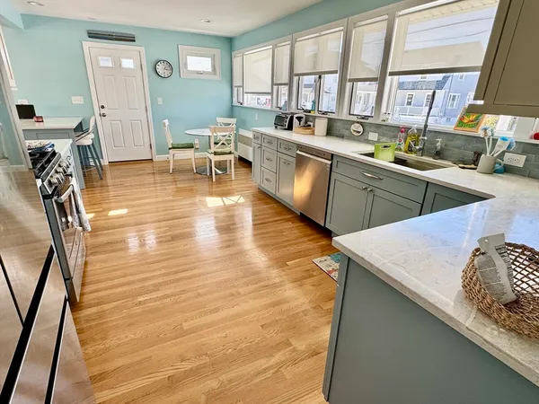 a kitchen with stainless steel appliances granite countertop a sink dishwasher a stove with wooden cabinets and floor