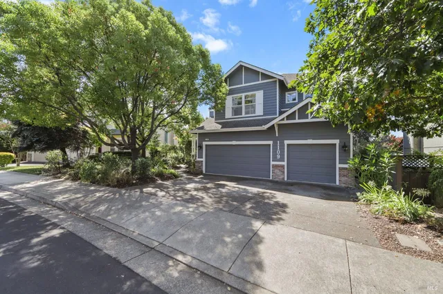 a front view of a house with a garden and trees