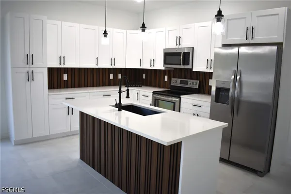 a kitchen with stainless steel appliances granite countertop a sink a microwave a refrigerator and a stove